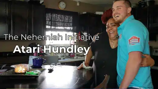Two people stand smiling and hugging in a kitchen. Text over the image reads