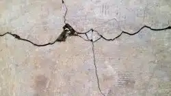 A close up view of cracked concrete surface with visible texture and small debris
