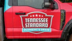 Red truck door with "Tennessee Standard Plumbing & Drain" logo in white and teal, featuring stars above the text—a trusted choice as East Tennessee weather impacts plumbing year-round.