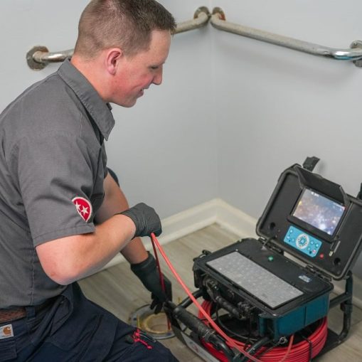 A technician uses a video inspection device to examine plumbing in a bathroom, viewing footage on a monitor—an essential step before drain cleaning in Knoxville.