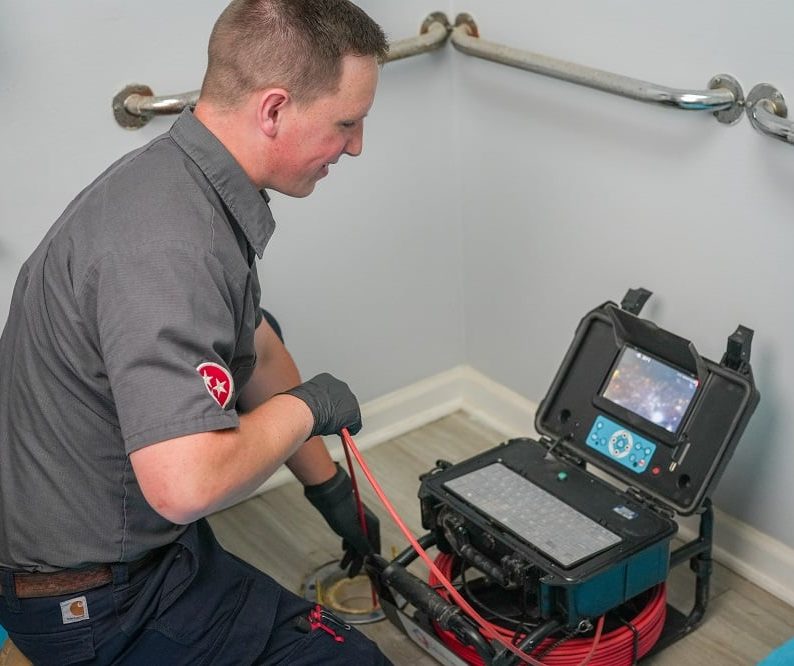 A technician uses a video inspection device to examine plumbing in a bathroom, viewing footage on a monitor—an essential step before drain cleaning in Knoxville.