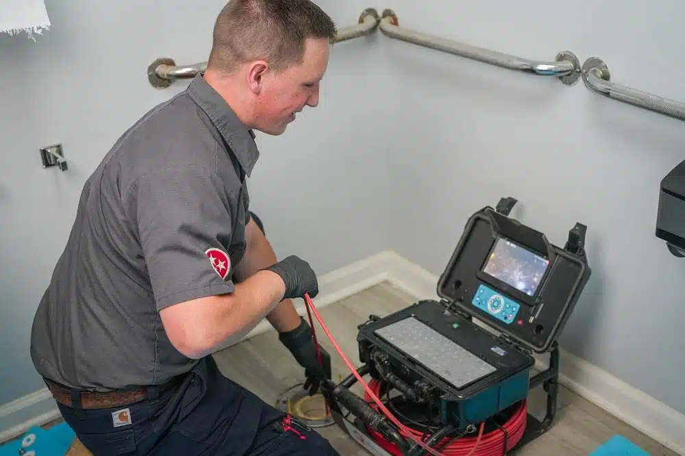 A technician uses a video inspection device to examine plumbing in a bathroom, viewing footage on a monitor, an essential step before drain cleaning in Knoxville.