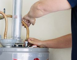 Adult male making adjustments and tightening connections on new hot water heater