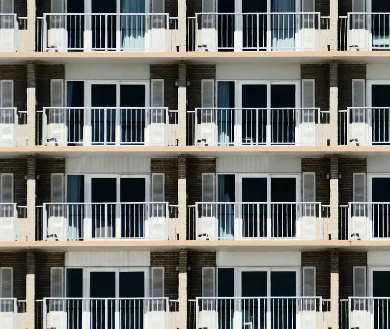 A symmetrical facade of a building with multiple identical balconies and glass doors arranged in a grid pattern.
