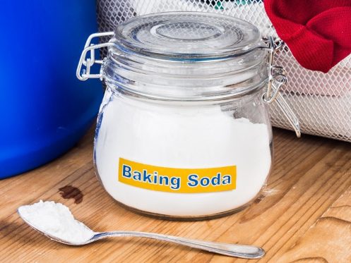 A glass jar labeled "Baking Soda" sits on a wooden surface with a spoonful of powder in front of it, perfect for DIY drain cleaning in Knoxville.