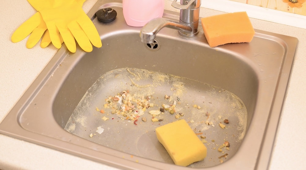 Close up on dirty clogging kitchen sink drain. Blur and selective focus of sink hole clogging up with food particles