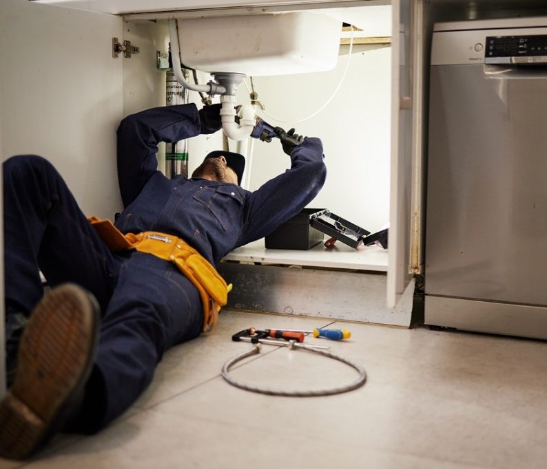 Kitchen, maintenance and renovation with a plumber on the floor of a home to fix a leak, issue or p.