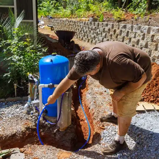 man working on filter for private well system