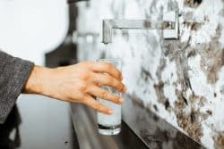 A person fills a clear glass with water.