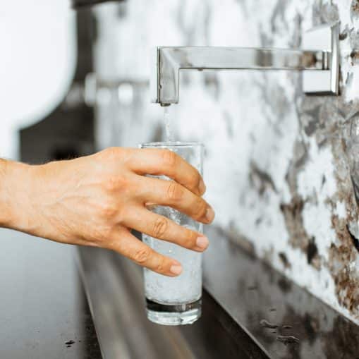 A person fills a clear glass with water.