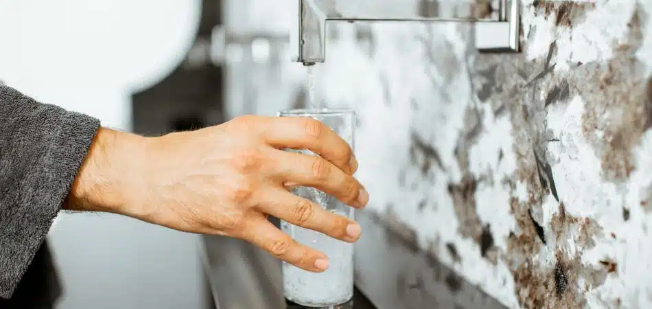 A person fills a clear glass with water.