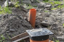 Inspection of the sewage system with a closed cast iron manhole, visible plastic pipes.