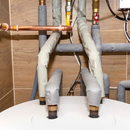 Water tank and gas pipes for a modern gas boiler in a home boiler room, lined with ceramic tiles.