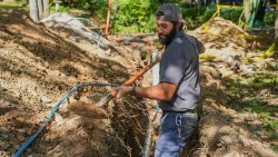 Professional plumber performing sewer line replacement in a residential yard
