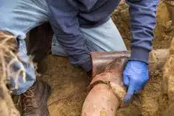 Worker fixing damaged clay sewer pipe, one of the common sewer line materials used in older homes.