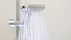 Close-up of a modern handheld showerhead spraying water, mounted on a metal rail against a plain background—a common sight when hot water runs out fast in Maryville.