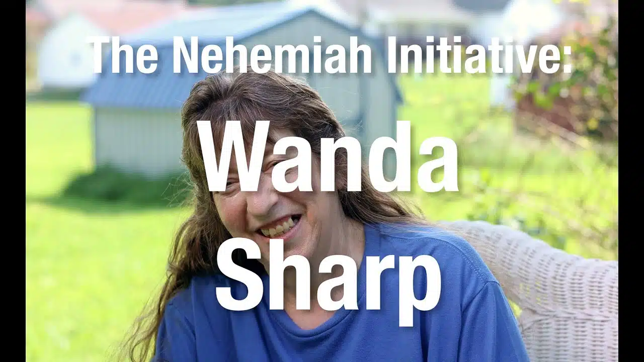 A woman with long brown hair, wearing a blue shirt, sits outdoors on a chair. The text reads: