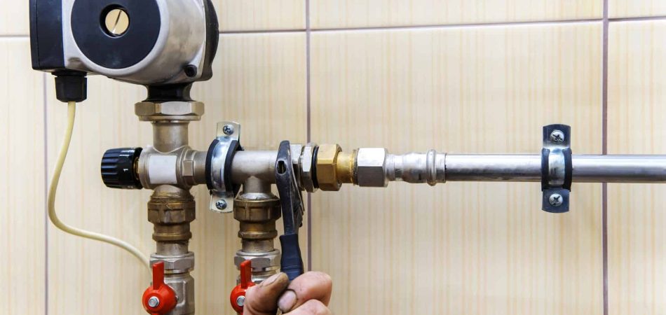 Plumber tightening a pipe connection on a water heating system.
